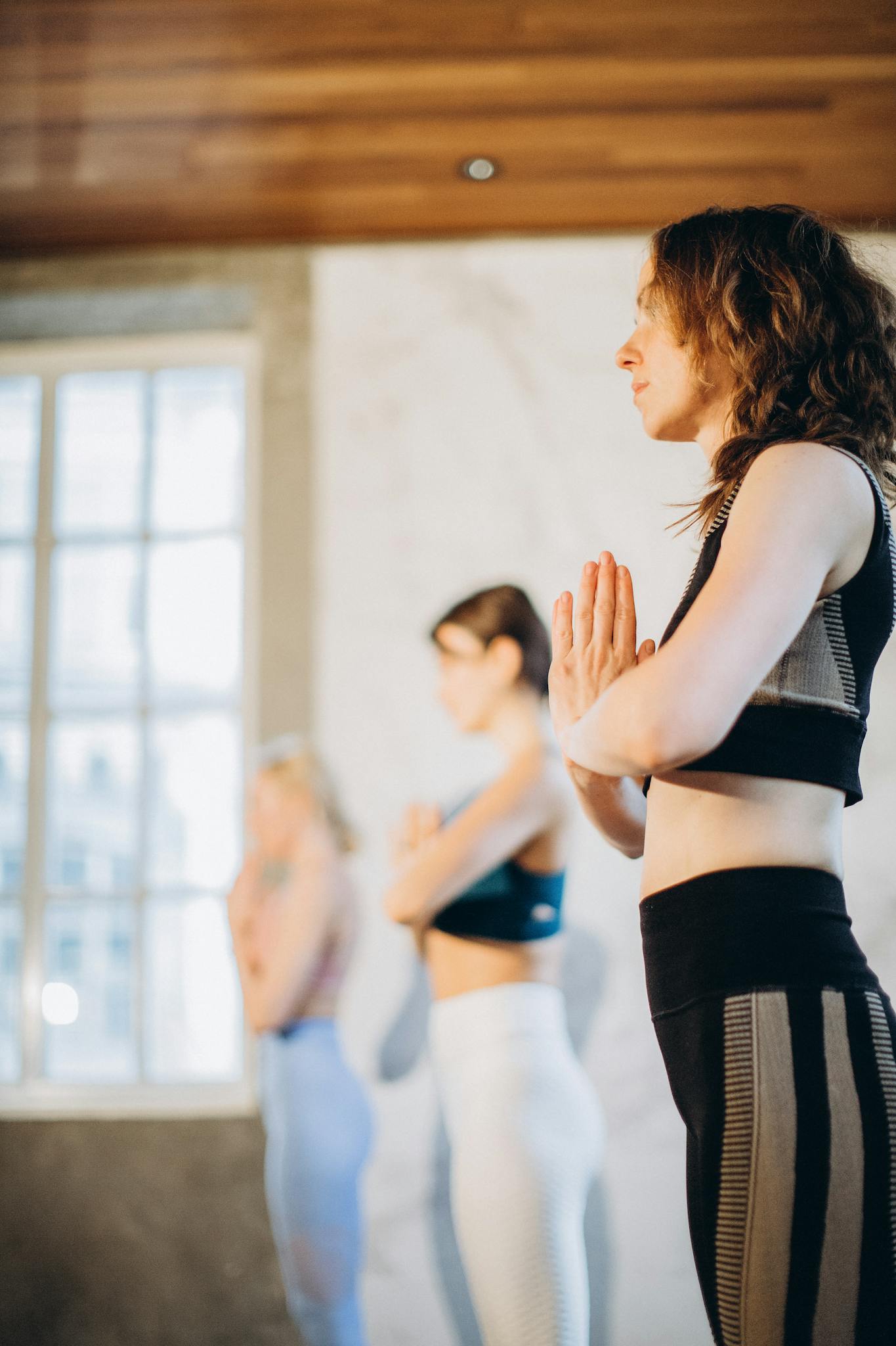Three women meditating in an indoor yoga session, focusing on relaxation and wellness.
